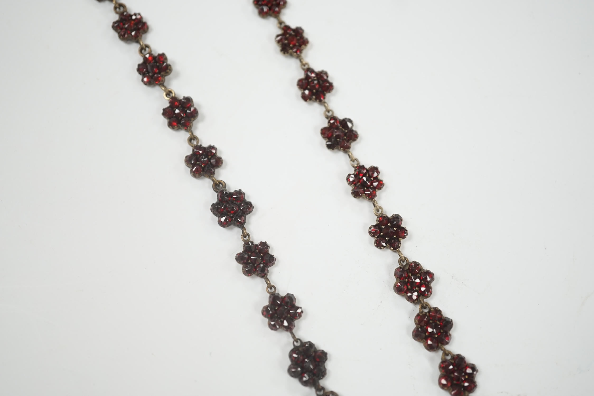 A Victorian gilt metal and facet cut garnet cluster set mourning drop pendant necklace, overall 50cm.